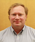 Headshot: Gentleman in white buttondown top smiling at the camera.