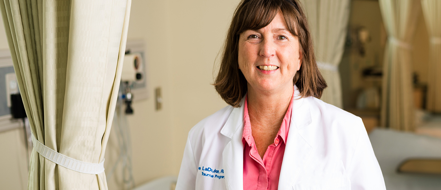 woman in a white lab coat standing in a hospital room by a curtain