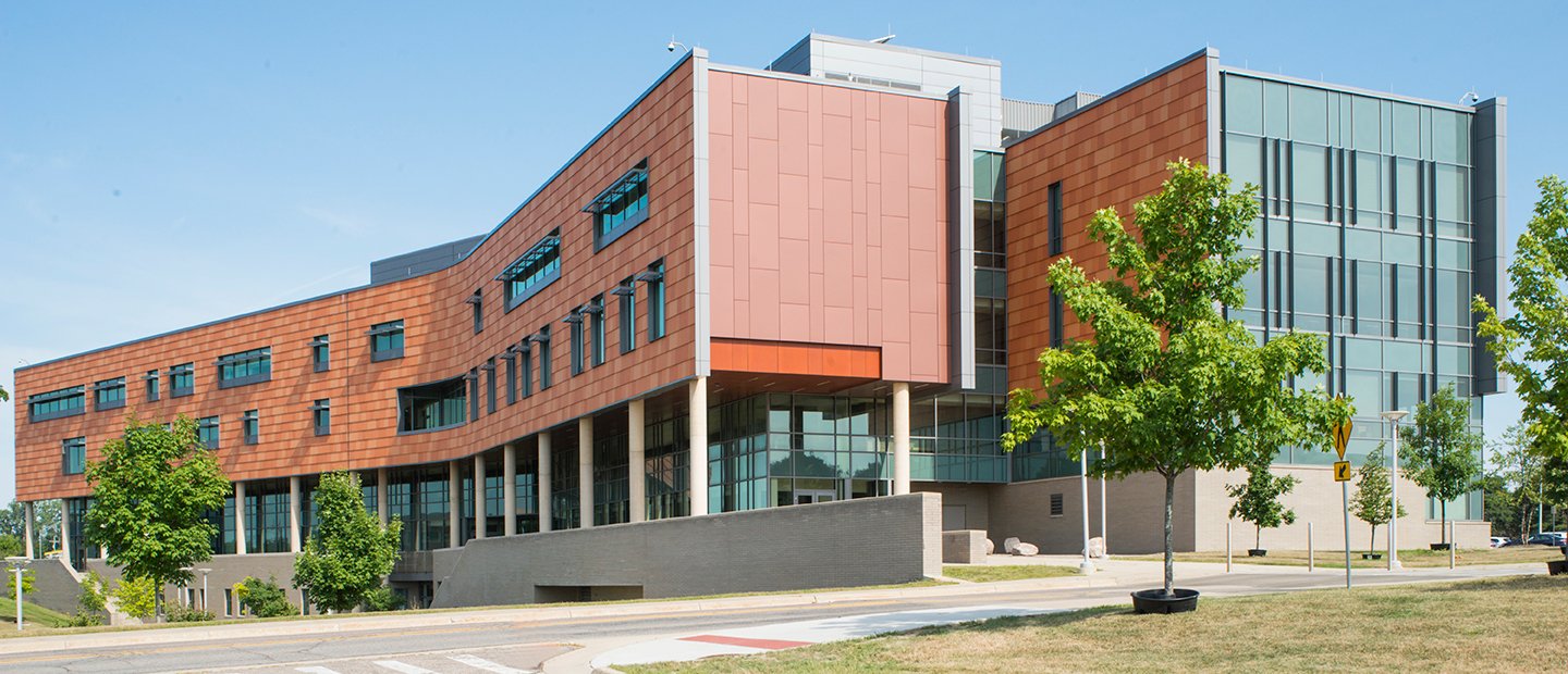 exterior of a brick and glass building with green trees around it