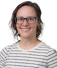 Headshot: woman in a black and white striped shirt and glasses smiling at the camera