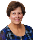 Headshot: Woman in dark top smiling at the camera