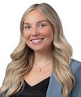 Headshot: Blonde woman in black top and med. blue jacket smiling at camera