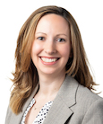 Headshot: Woman in polka dot top and grey jacket smiling at the camera