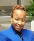 Headshot Woman in blue jacket smiling at the camera