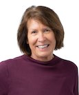 Headshot: Woman in burgundy top smiling at the camera