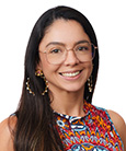 Headshot: Dark haired woman in multi-colored top smiling at the camera.