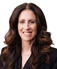 Headshot: Dark haired woman in black top smiling at the camera.